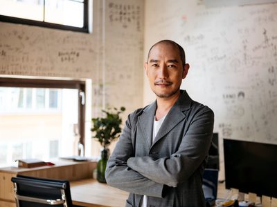 Man in 50s with arms crossed smiling towards camera with contented expression, executive, manager, confidence
