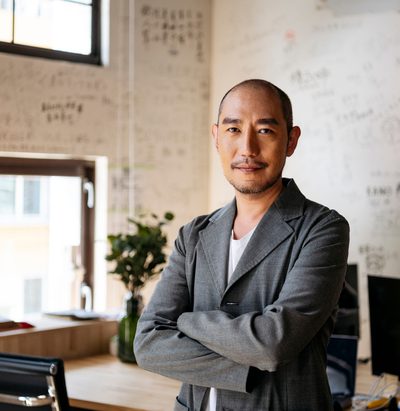 Man in 50s with arms crossed smiling towards camera with contented expression, executive, manager, confidence