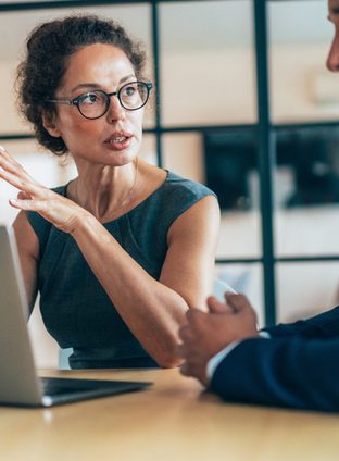 Two business people having a meeting and discussing new agreement. Working process in the office, businessman and business woman working together using laptop. Couple of business persons talking, they are engaged in a focused conversation