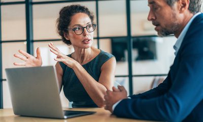 Two business people having a meeting and discussing new agreement. Working process in the office, businessman and business woman working together using laptop. Couple of business persons talking, they are engaged in a focused conversation