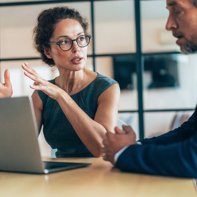 Two business people having a meeting and discussing new agreement. Working process in the office, businessman and business woman working together using laptop. Couple of business persons talking, they are engaged in a focused conversation