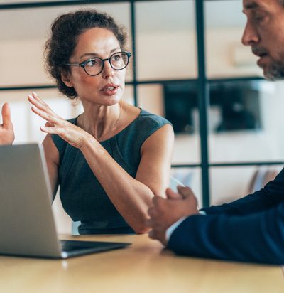 Two business people having a meeting and discussing new agreement. Working process in the office, businessman and business woman working together using laptop. Couple of business persons talking, they are engaged in a focused conversation