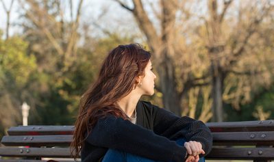 Pensive young woman in the park looking away.