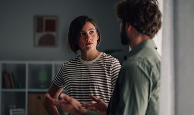 Young couple having serious discussion indoors. Woman listening intently to man talking, communicating relationship issues