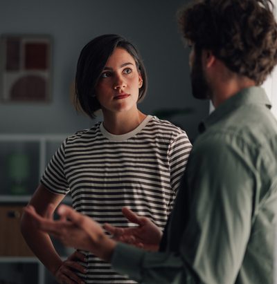 Young couple having serious discussion indoors. Woman listening intently to man talking, communicating relationship issues