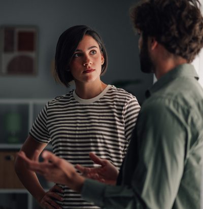 Young couple having serious discussion indoors. Woman listening intently to man talking, communicating relationship issues