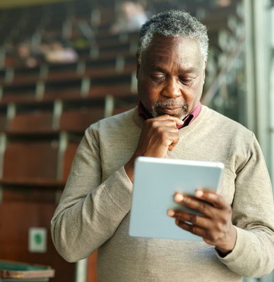 African American male teacher brainstorming while working on digital tablet during a class at lecture hall.