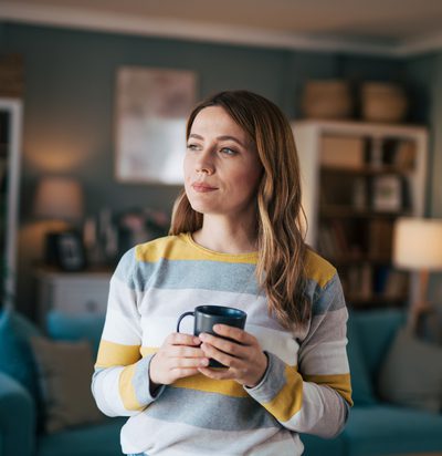 Mature woman looks out the window and drinks coffee.